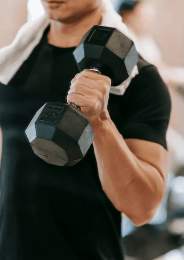 Sportininkas atlieka jėgos treniruotę su hanteliais